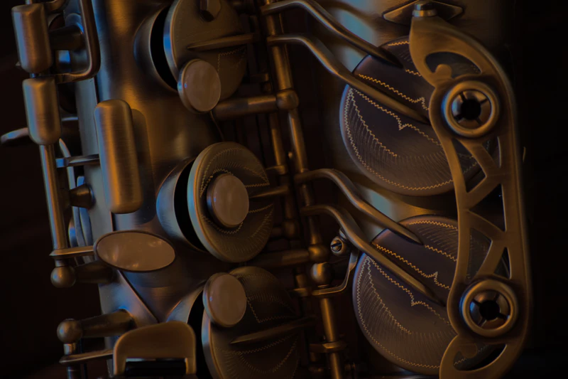Close-up of the keys and engraved key guard of a saxophone in warm low light